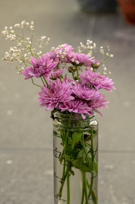 Elegant arrangement of purple chrysanthemums and baby's breath in a glass vase, perfect for home decor.